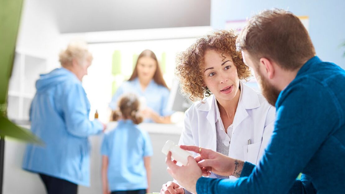 A female doctor speaks seriously to a younger male patient in the waiting room