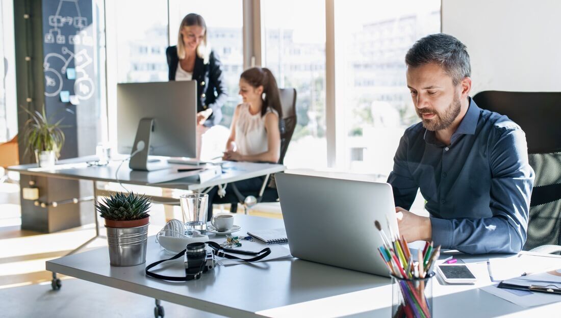 ServiceNow people are working in a modern office setting with the sun shining through the windows
