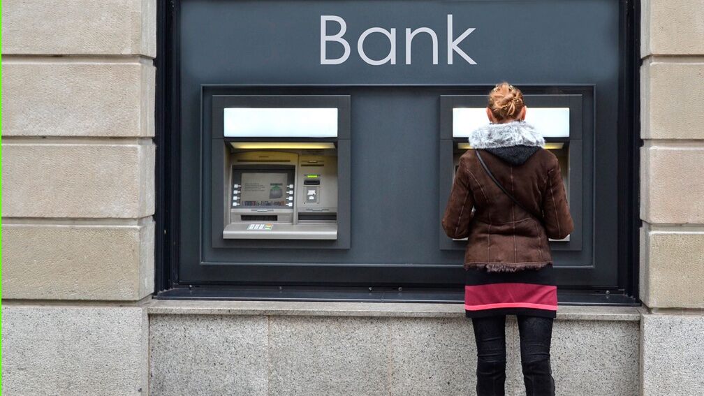 A woman stands with her back to the camera at an Banqsoft ATM