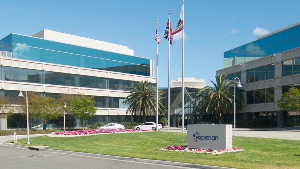 A view of the Experian office building in California on a sunny day with flags waving and palm trees
