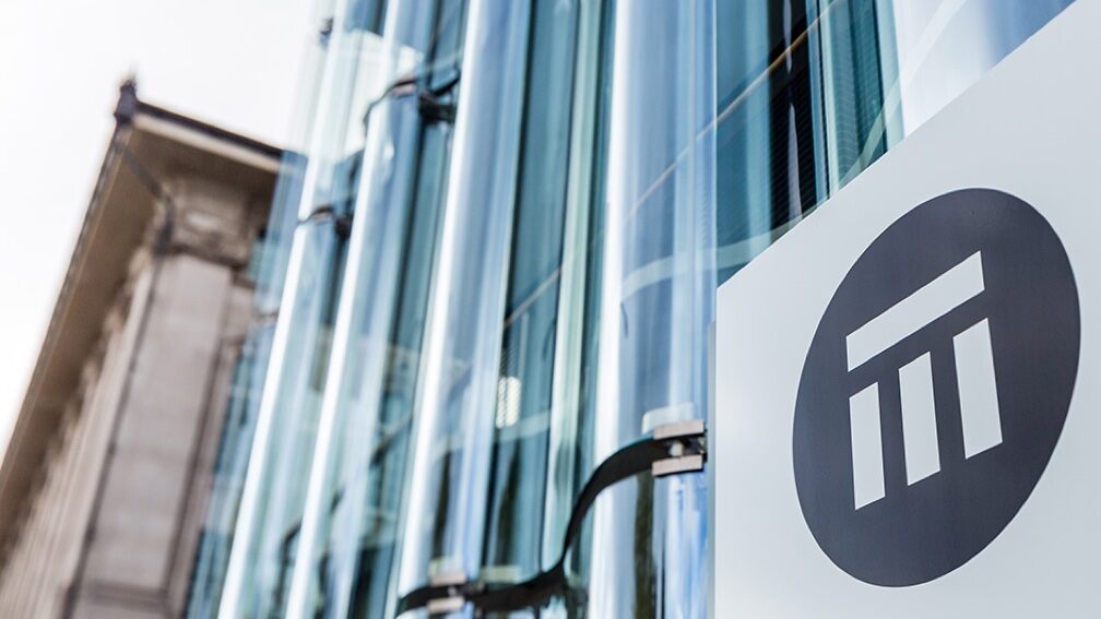 The Swiss Re logo at the front of a modern glass office building